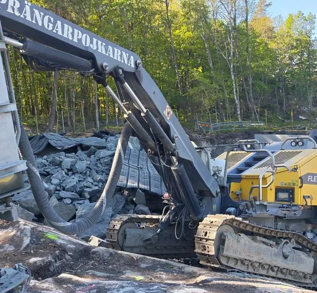 Grävmaskin med Sprängarpojkarnas namn på bommen vid ett bergparti