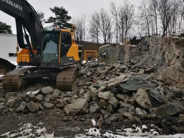 Grävmaskin bland sprängsten på en villatomt